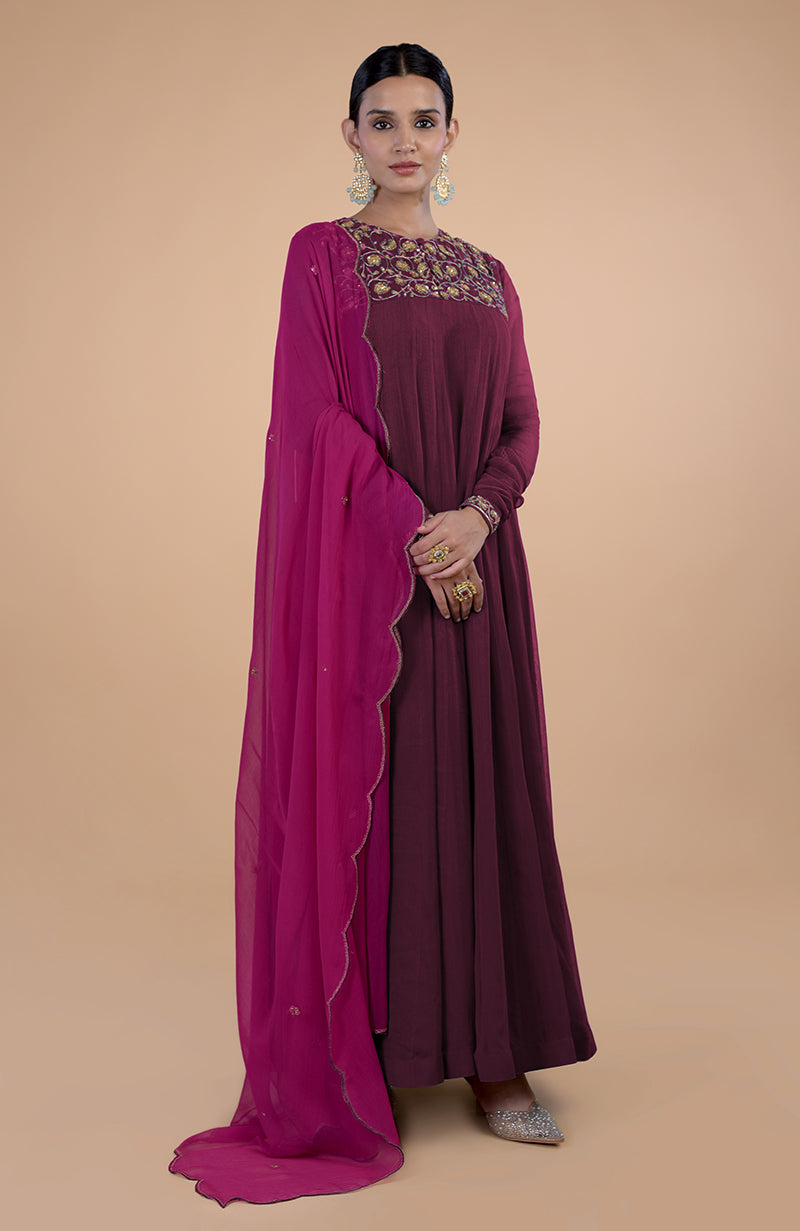 A woman models a burgundy anarkali with zardozi embroidery and a pink dupatta.