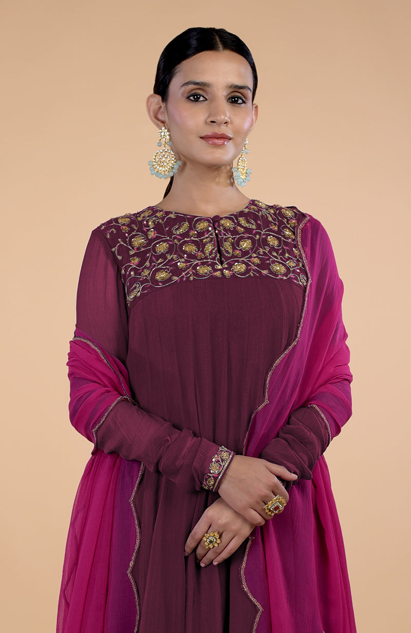 A woman models a burgundy and pink zardozi embroidered anarkali set.