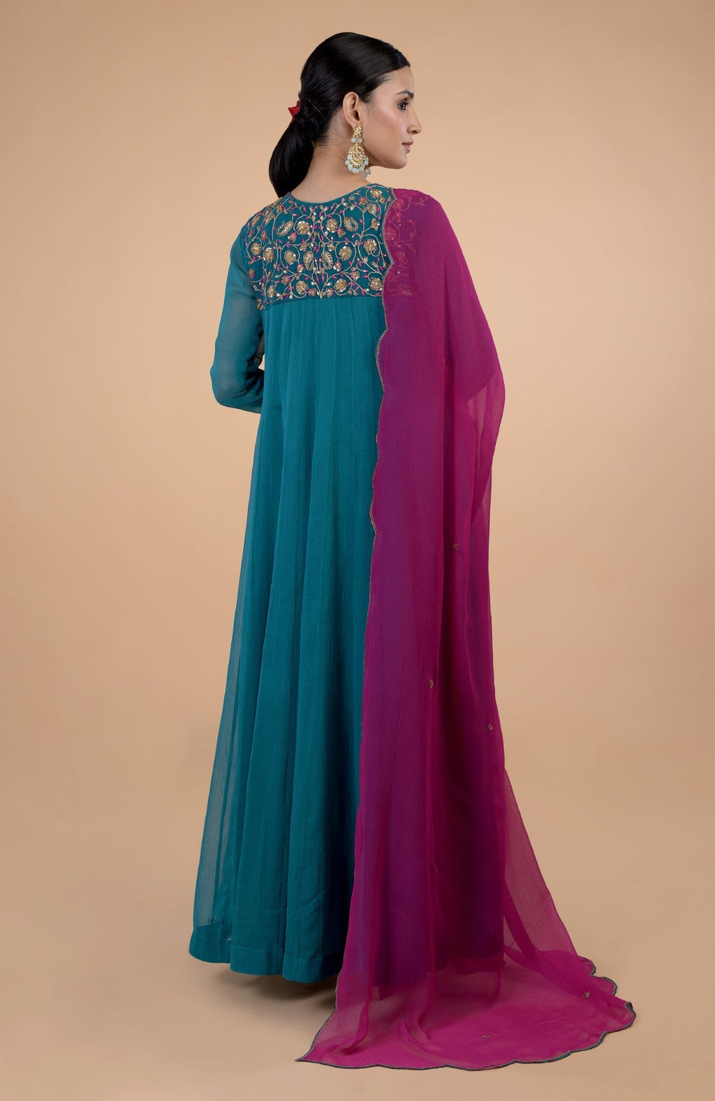 A woman models a teal anarkali with zardozi embroidery and a pink dupatta.