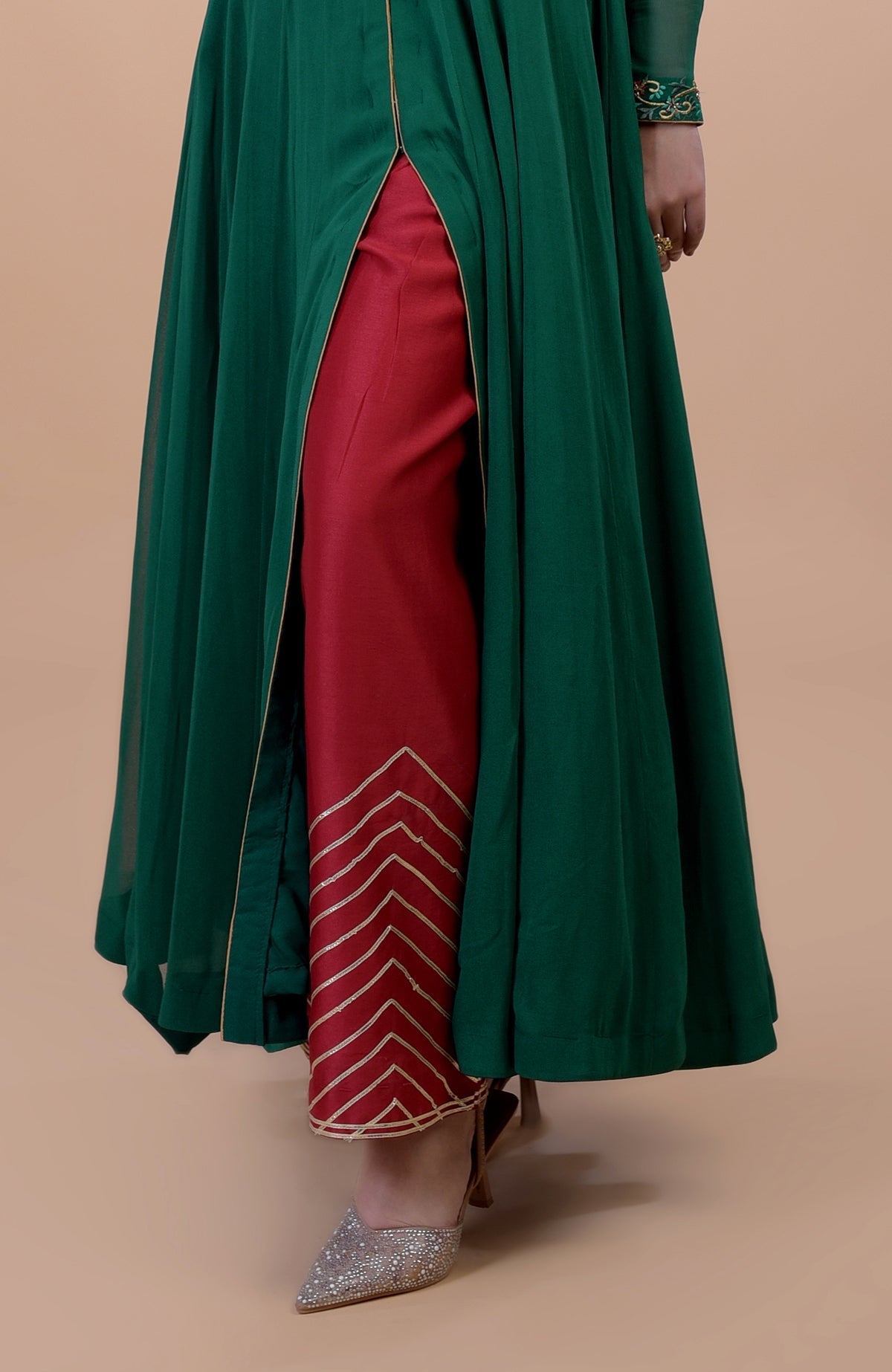 Emerald green anarkali with red pants featuring gold chevron embroidery and embellished shoes.