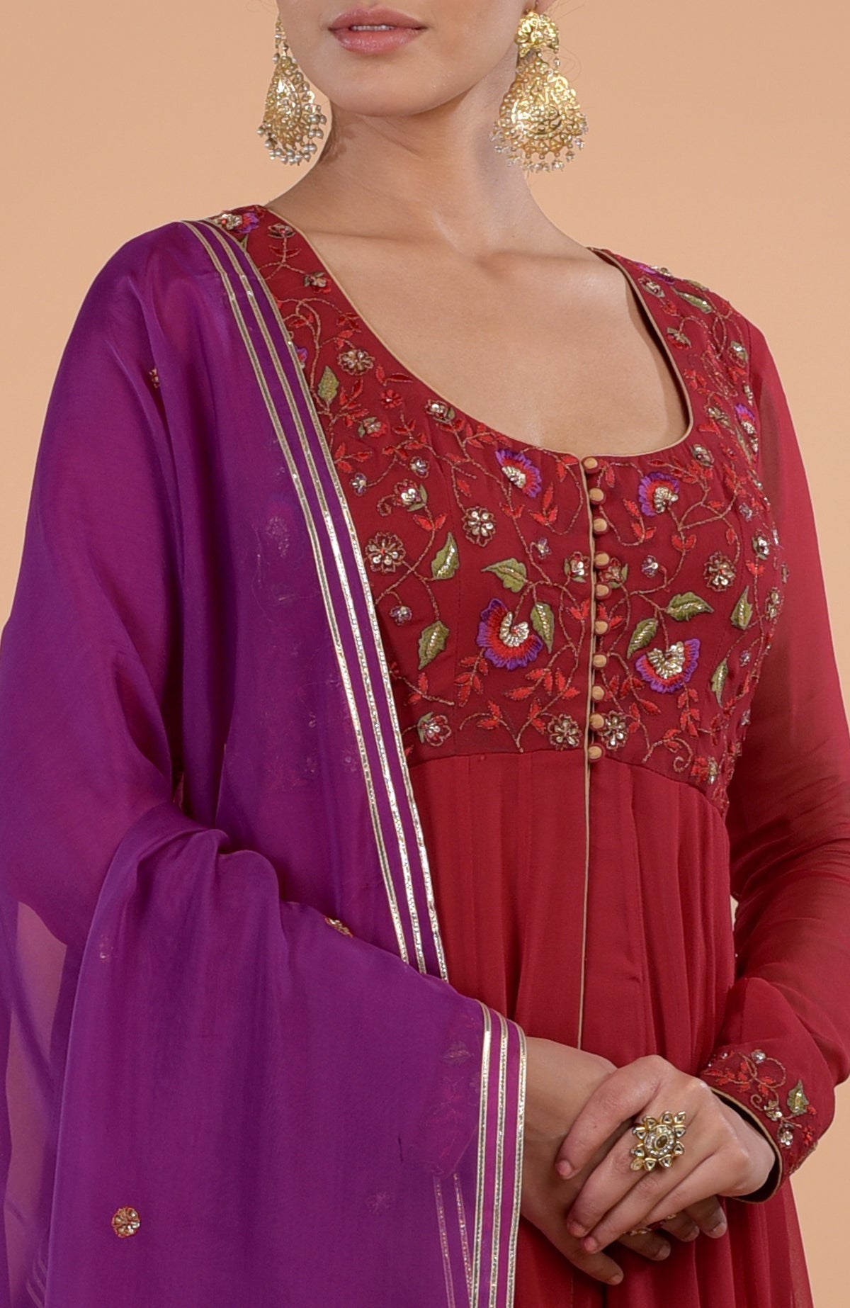 A woman models a blood red and purple anarkali set with floral embroidery.
