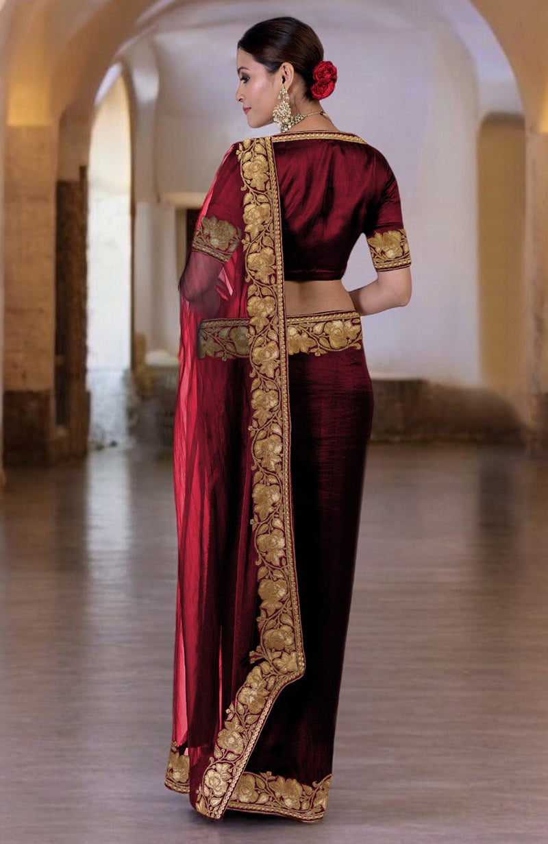 A woman models a blood red Kashmiri Tilla embroidered saree with a matching blouse.