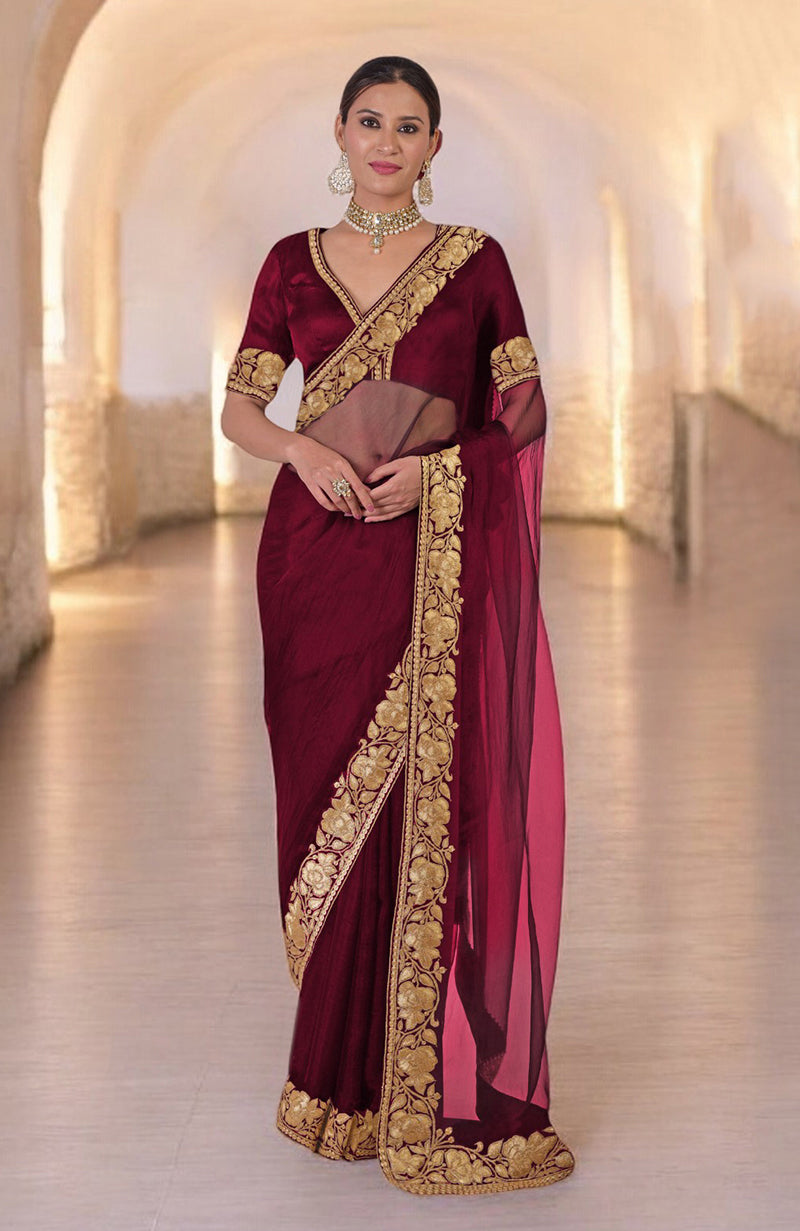 A woman models a blood red Kashmiri Tilla embroidered saree with a matching blouse.