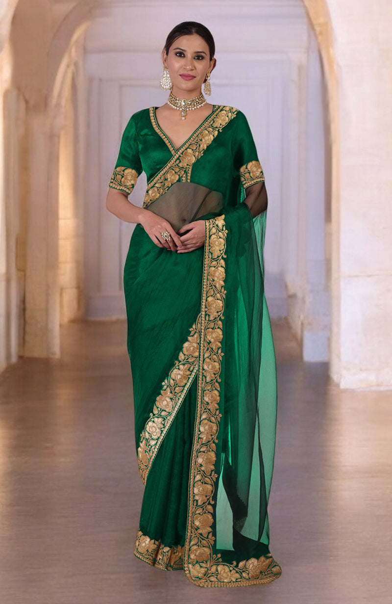 A woman models a green saree with gold floral embroidery and a matching blouse.