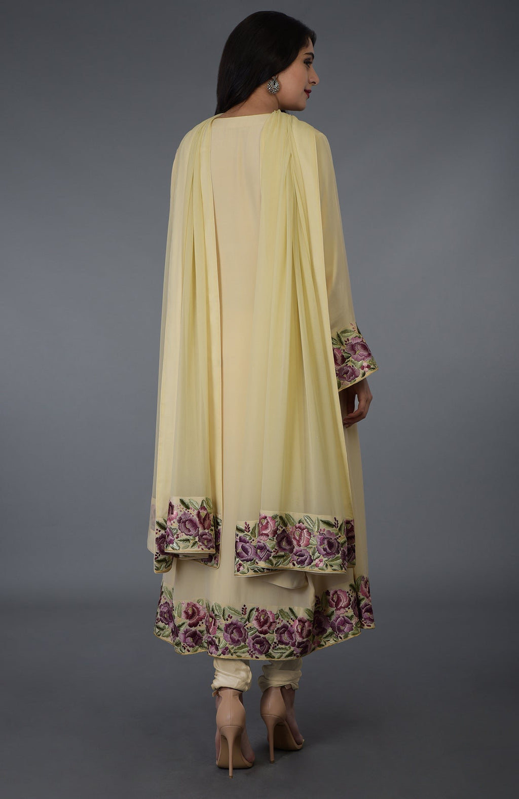 A woman models a lemon chiffon Parsi Gara embroidered suit with floral patterns.