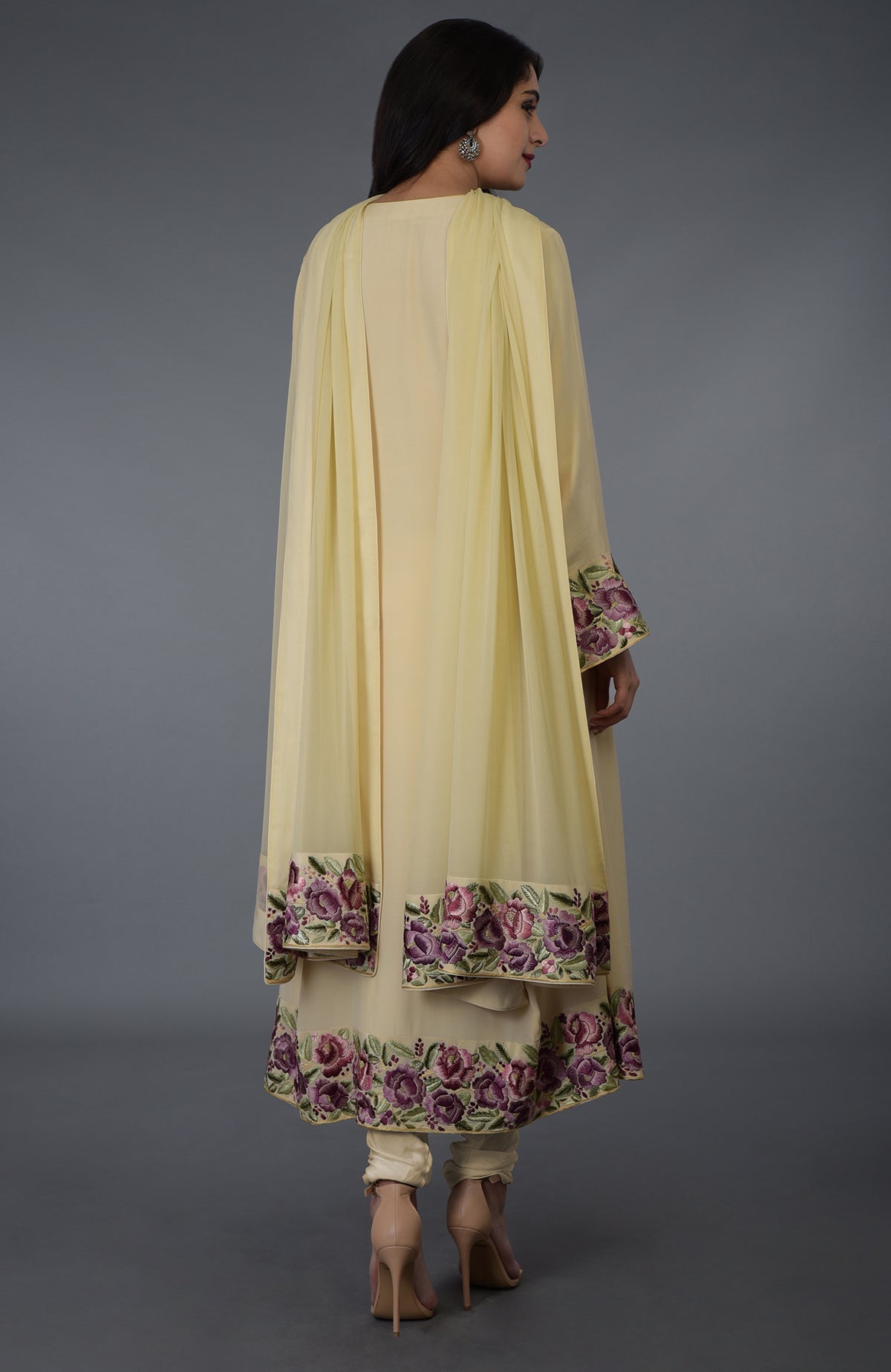 A woman models a lemon chiffon Parsi Gara embroidered suit with floral patterns.