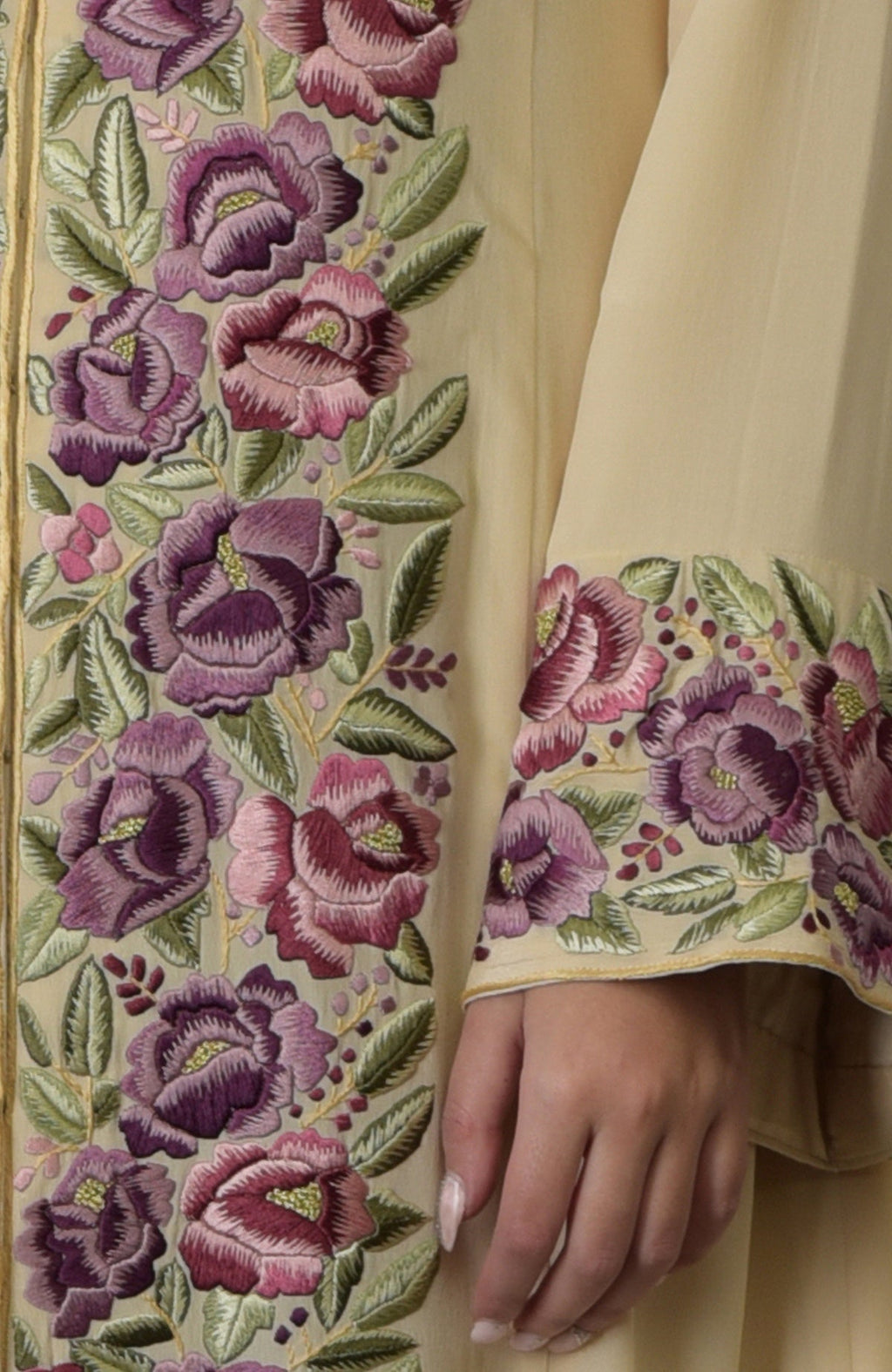 Lemon chiffon Parsi Gara embroidered suit with floral patterns and a woman's hand.