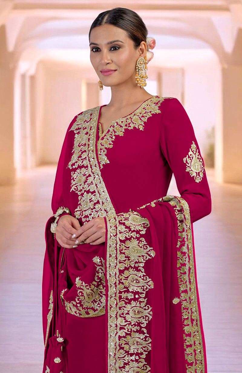 A woman in a bright rose gold Kashmiri kurta set with intricate gold embroidery.
