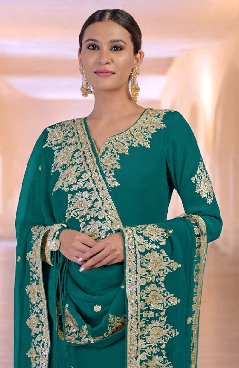 A woman models a teal kurta set with intricate gold embroidery and matching earrings.