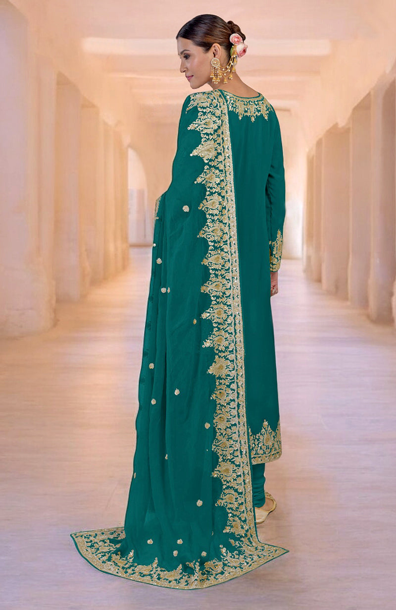 Woman in a teal kurta set with gold embroidery and a matching dupatta.