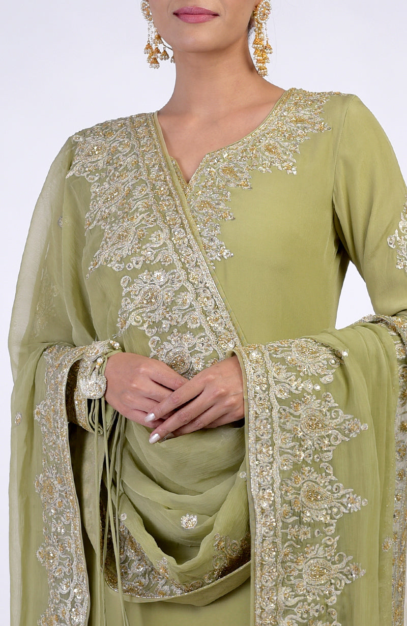 A woman models a bog green kurta set with gold Kashmiri tilla and zardozi embroidery.