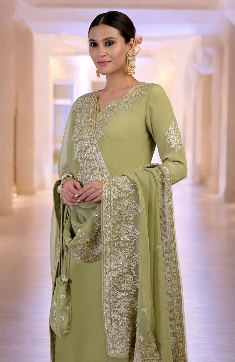 A woman models a bog green kurta set with gold Kashmiri tilla and zardozi embroidery.