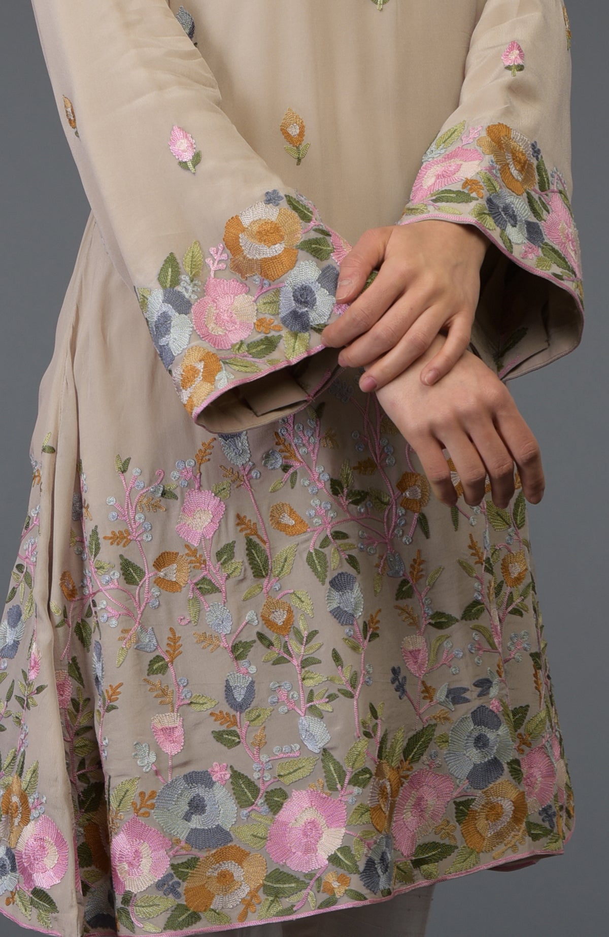 Beige Parsi embroidered tunic suit with colorful floral patterns and bell sleeves.
