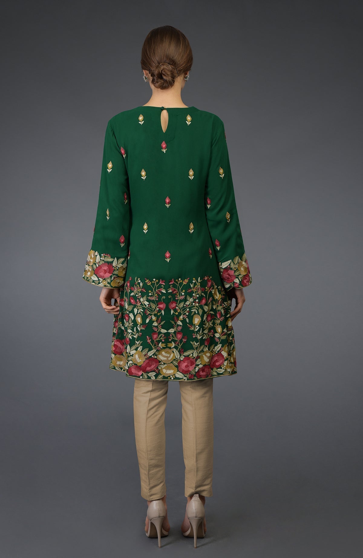 A woman from behind wearing a bottle green Parsi embroidered tunic suit.