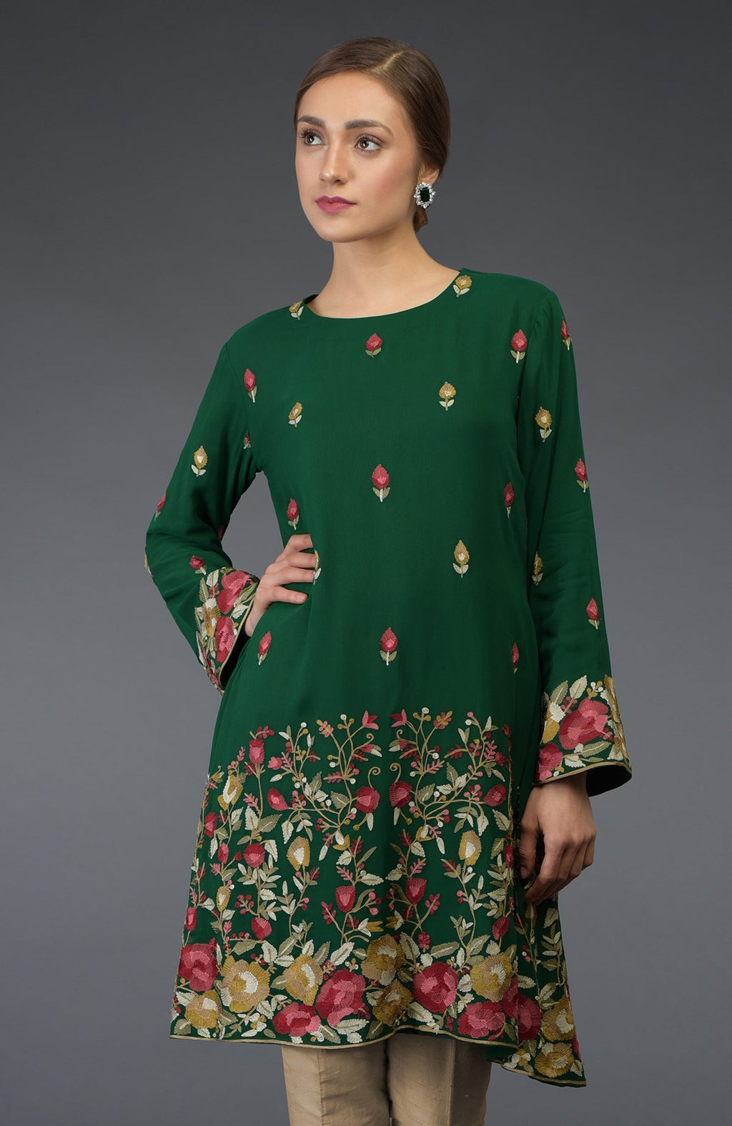 A woman models a bottle green tunic with Parsi floral embroidery.