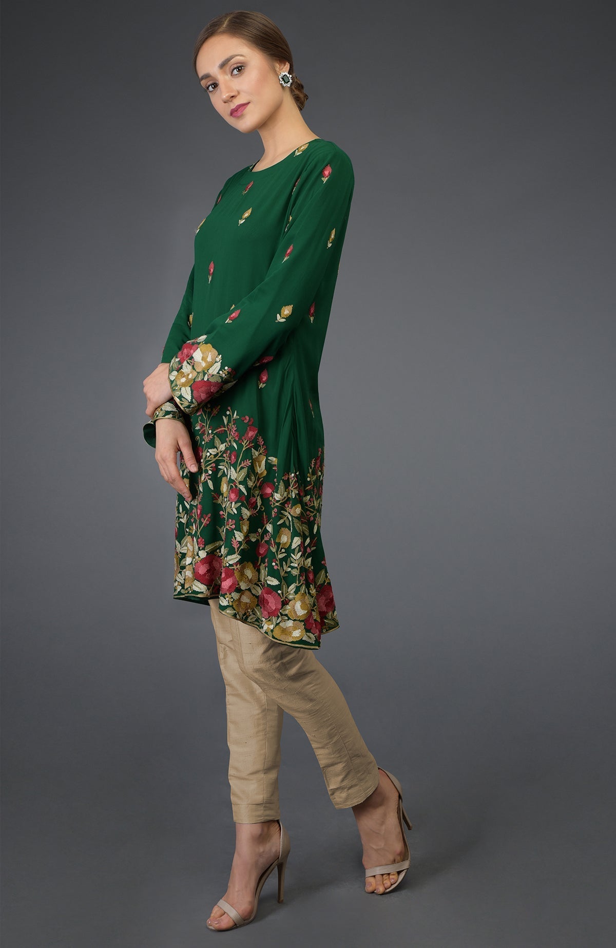 A woman models a bottle green Parsi embroidered tunic suit with beige pants.
