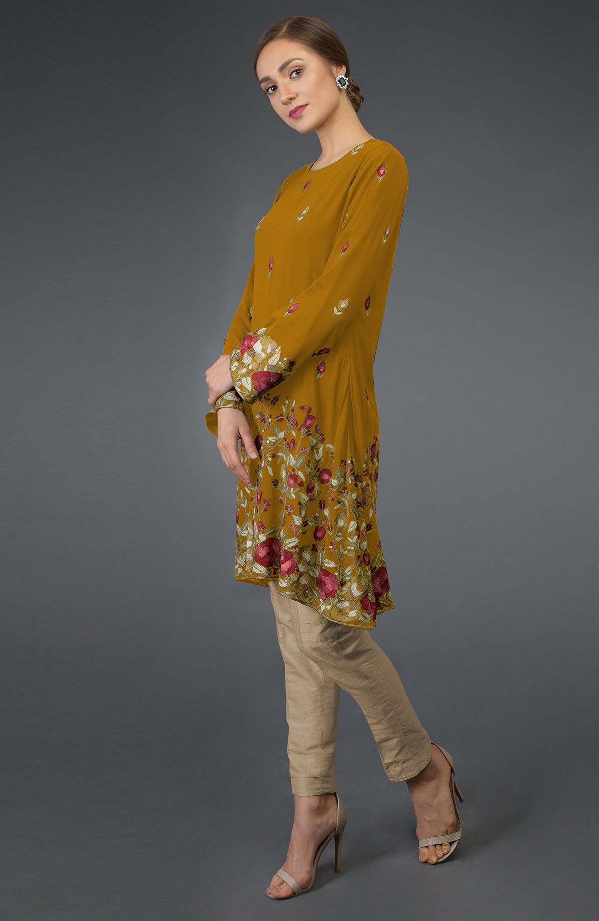 A woman models a dijon mustard tunic with Parsi embroidery and beige pants.