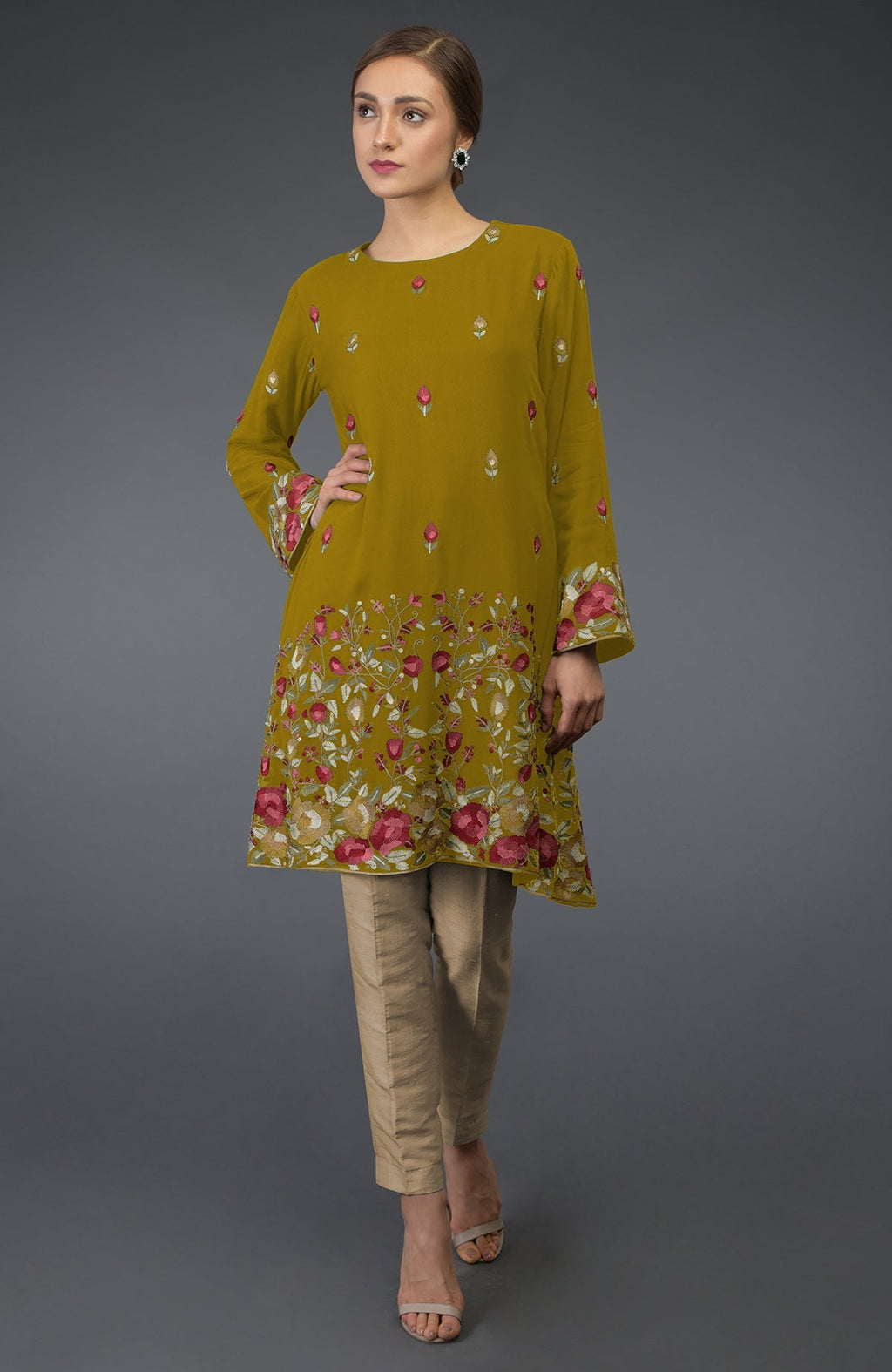 A woman models a mustard tunic with Parsi embroidery and beige pants.