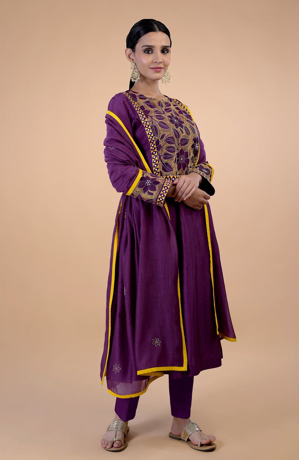 A woman models a plum Kantha hand-embroidered kalidaar kurta set with yellow trim.
