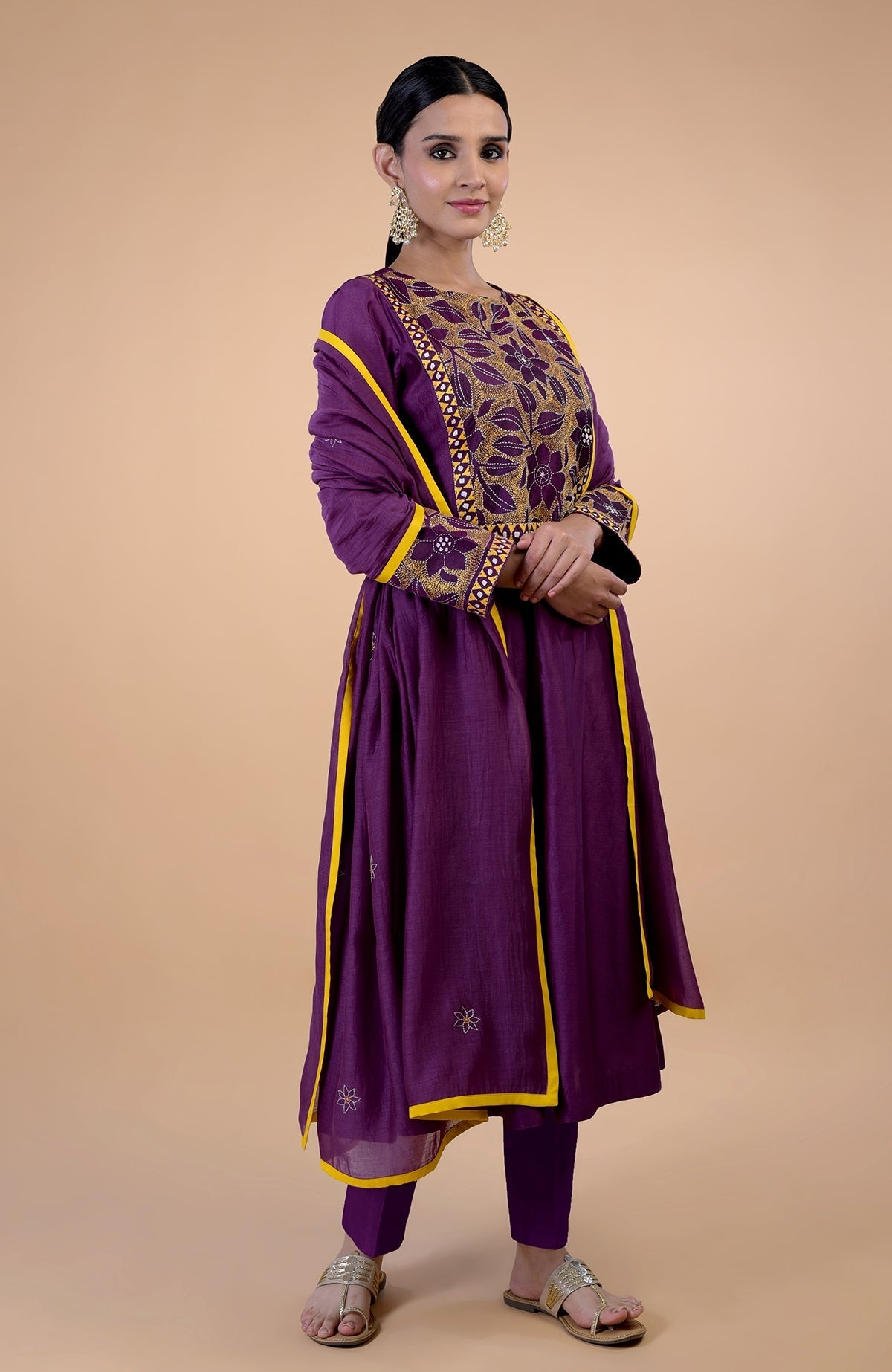 A woman models a plum Kantha hand-embroidered kalidaar kurta set with yellow trim.