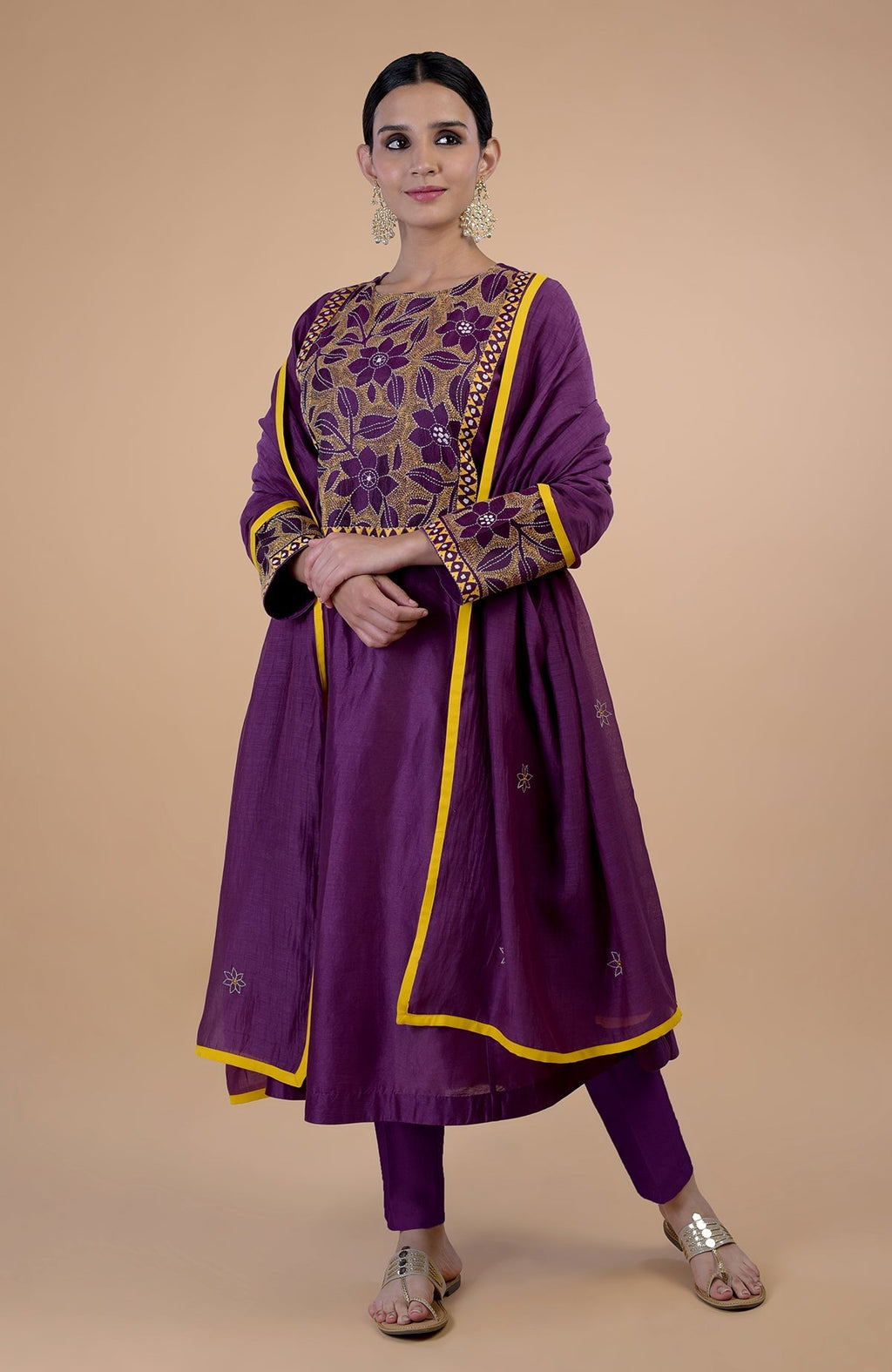 A woman models a plum Kantha hand-embroidered kalidaar kurta set with yellow piping.