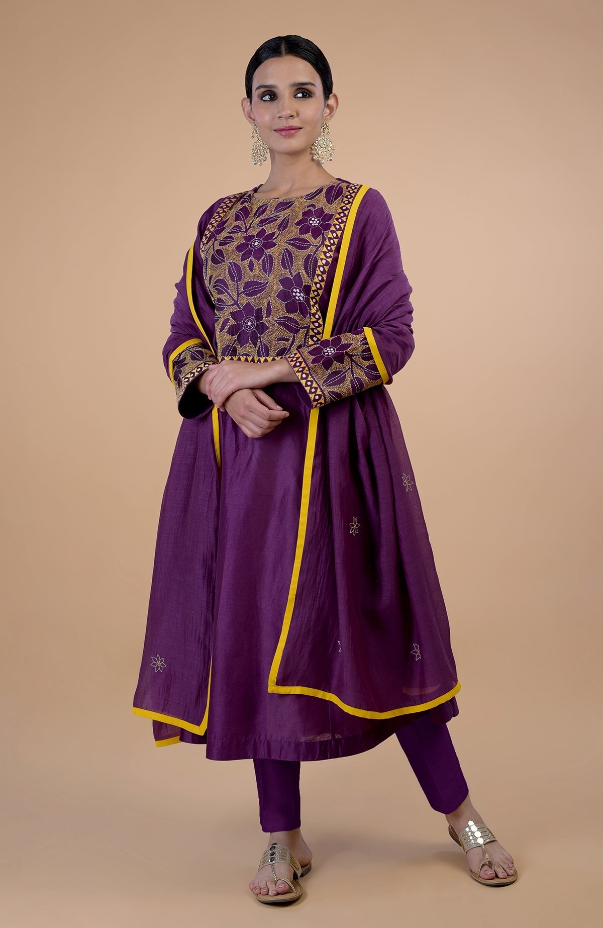 A woman models a plum Kantha hand-embroidered kalidaar kurta set with yellow piping.