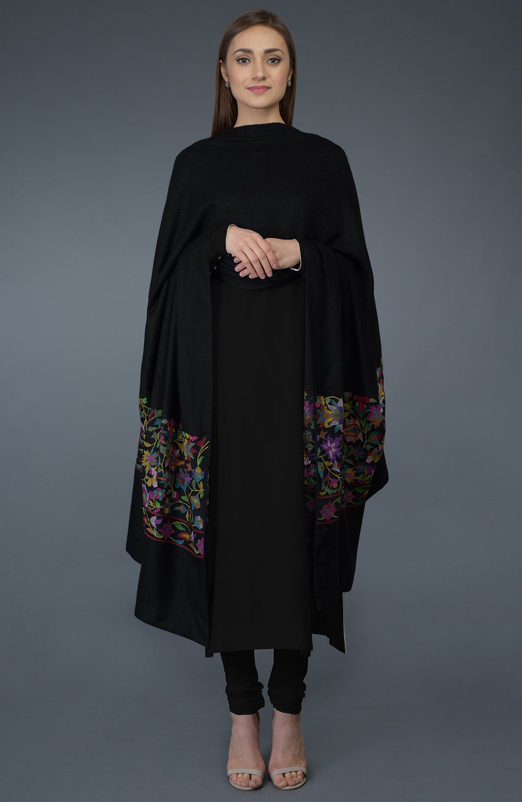 A woman models a black suit with a colorful floral embroidered dupatta.