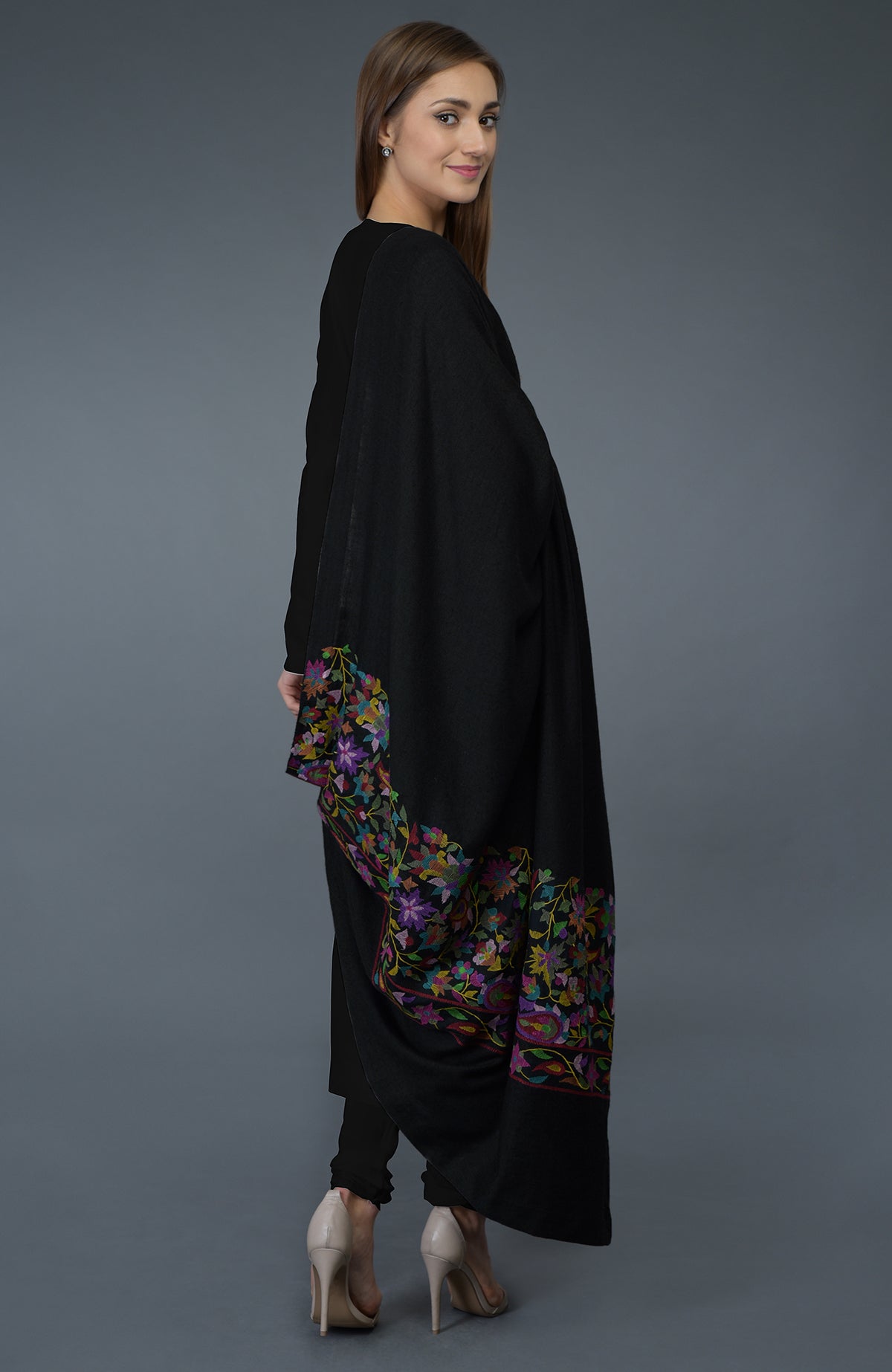 A woman models a black embroidered dupatta and suit with high heels.