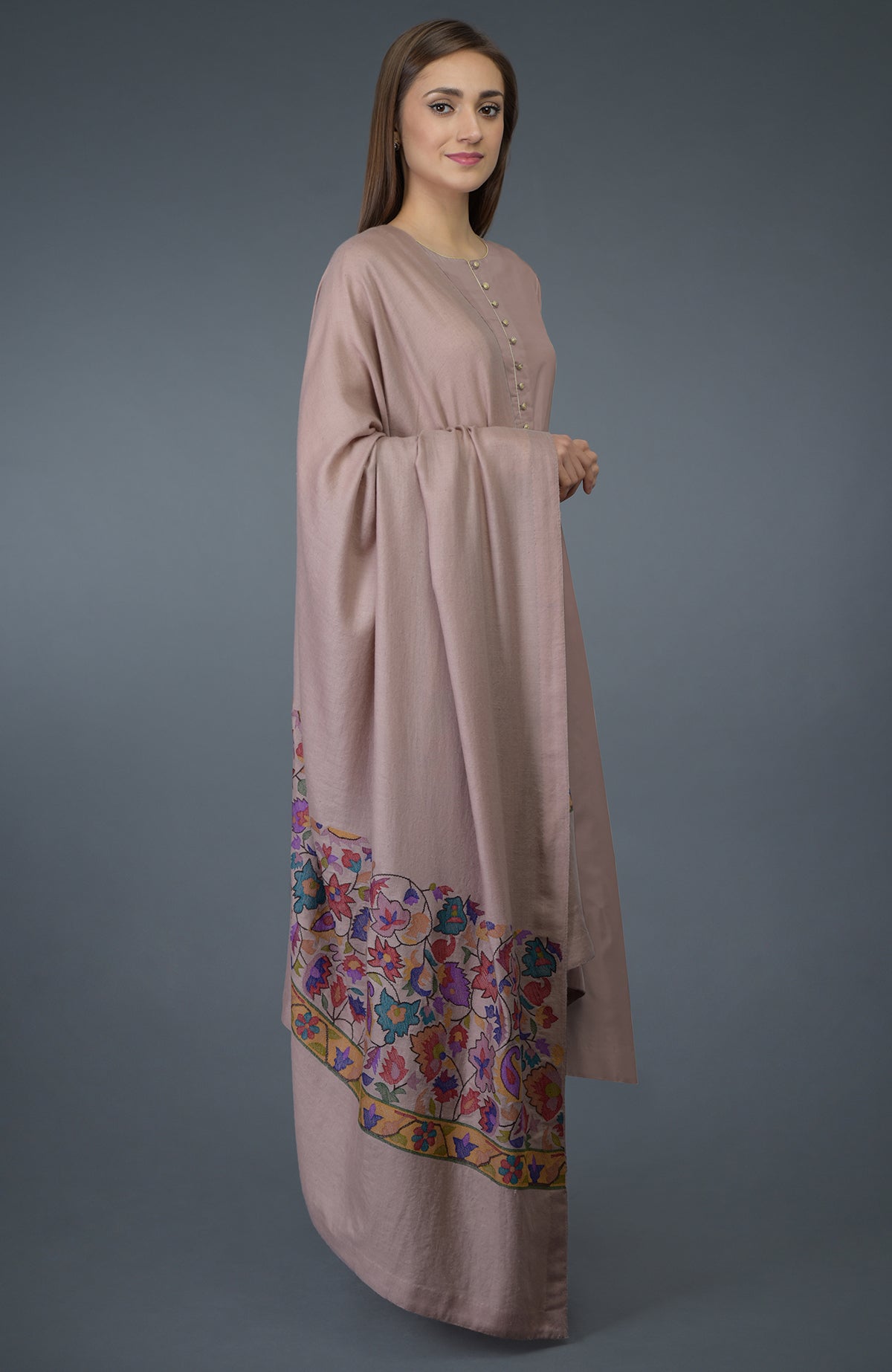 A woman models a dusty rose suit with a floral embroidered dupatta.