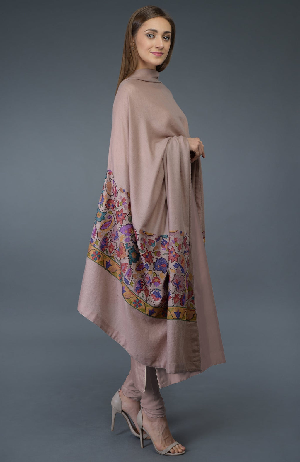 A woman models a dusty rose suit with a colorful embroidered dupatta and high heels.