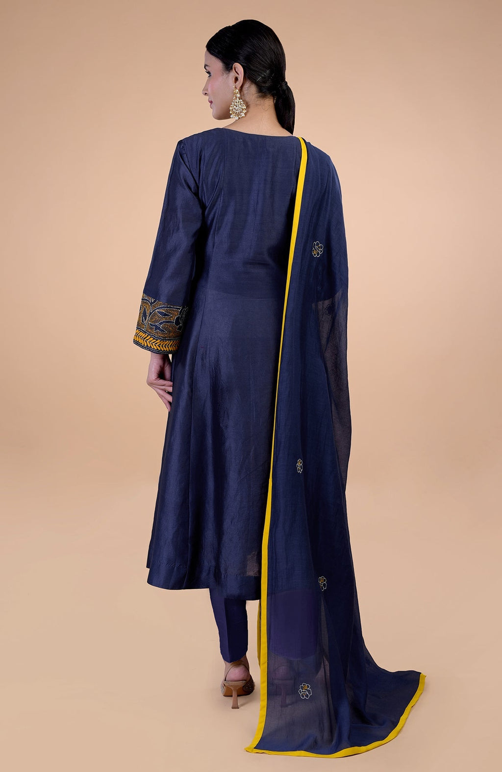 A woman from behind wears a navy blue kurta set with yellow Kantha embroidery and piping.