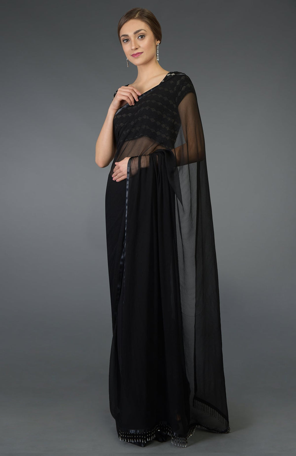 A woman models a black pure chiffon saree with a zardozi and beads work blouse.