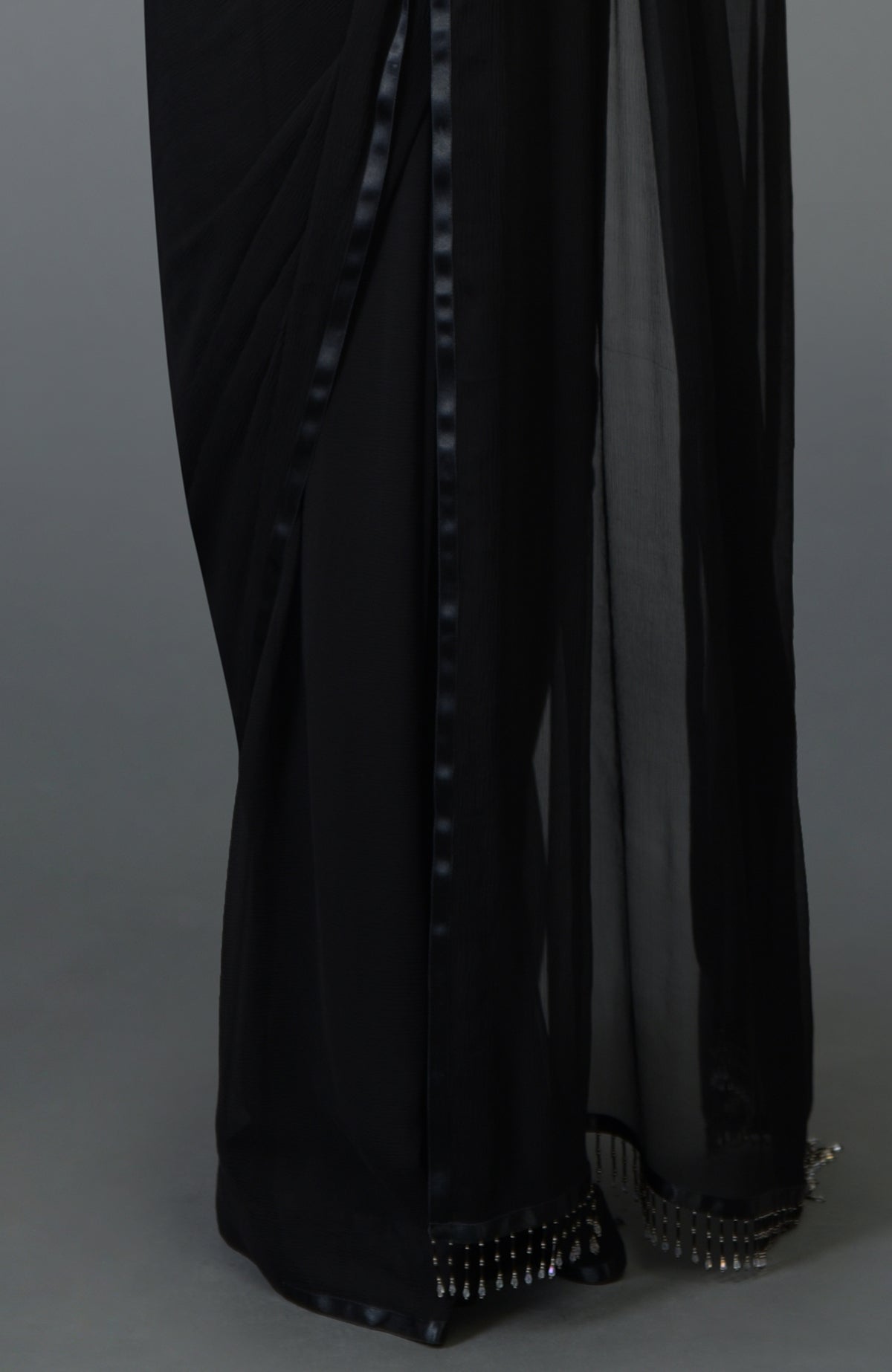 Black pure chiffon saree with satin border trims and beaded pallav fringe.