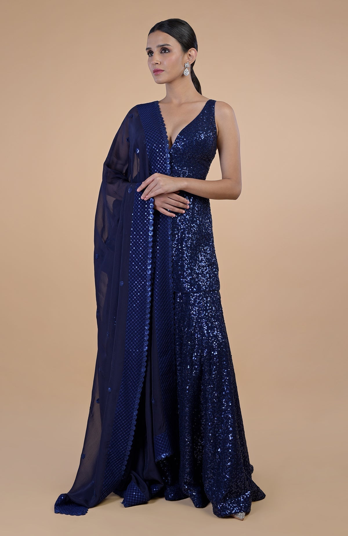 A woman models a sapphire blue sequin embroidered sharara set with a matching dupatta.