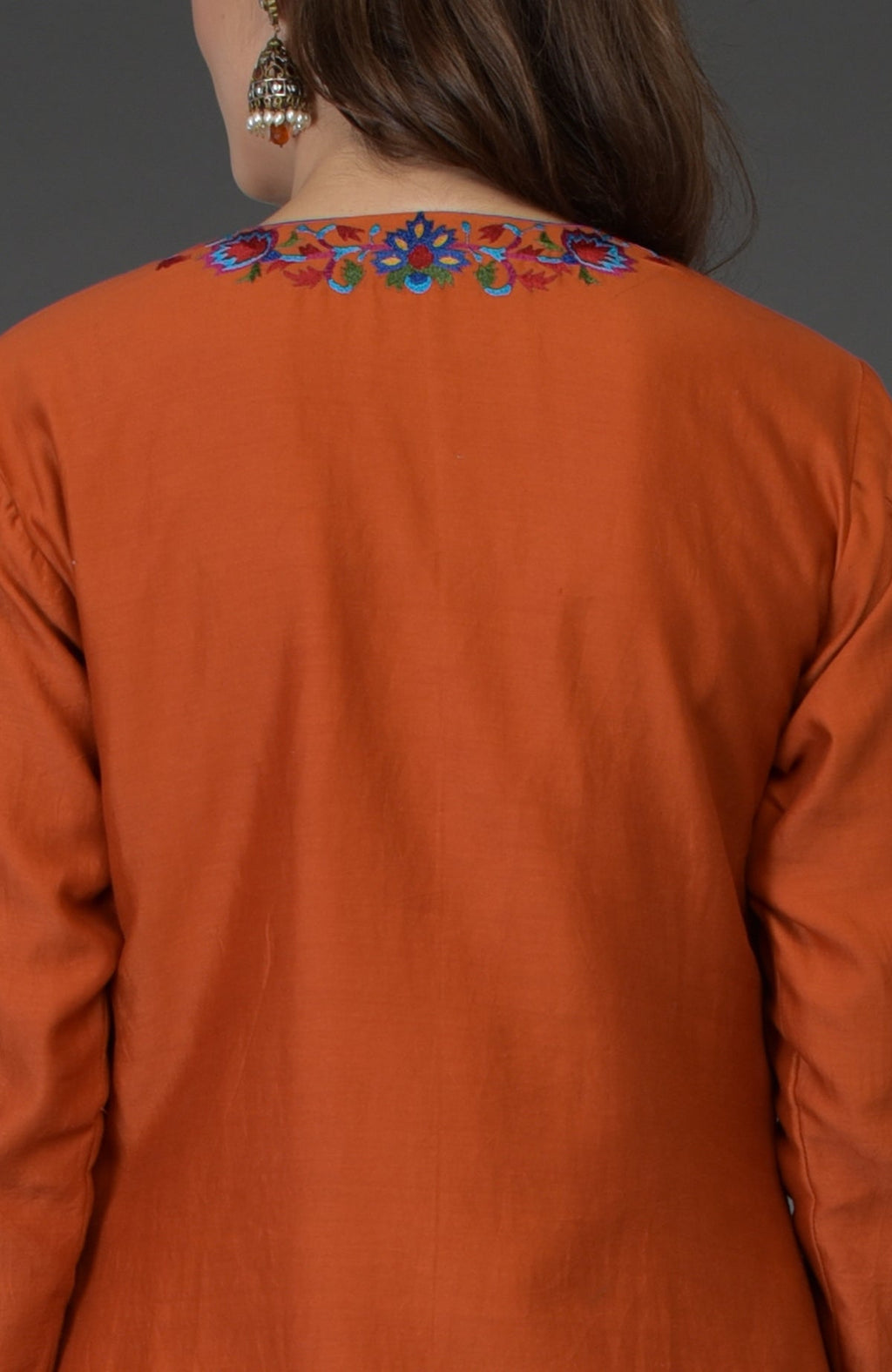 Back view of a burnt orange palazzo suit with colorful floral embroidery on the neckline.