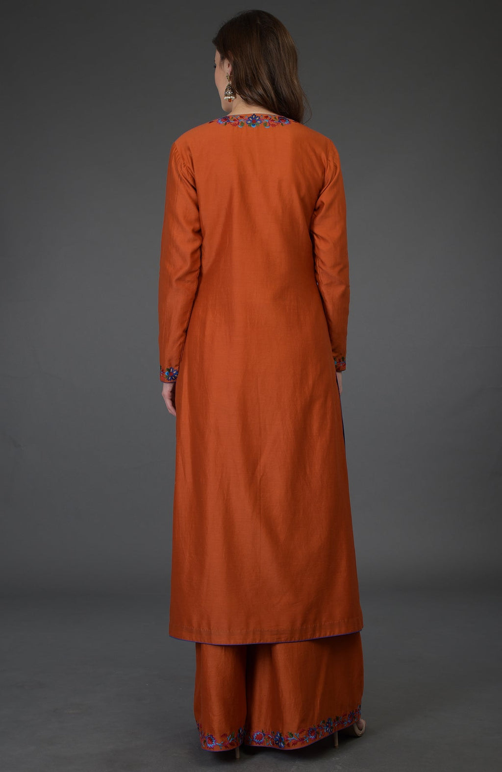 A woman from behind wears a burnt orange Kashmir Bagh inspired Farshi Palazzo Suit.