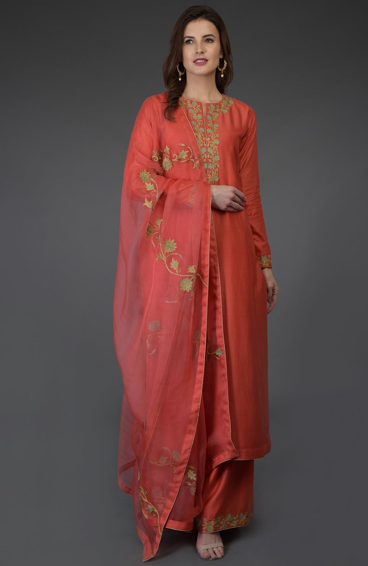 A woman models a chutney-colored palazzo suit with gold and green embroidery.