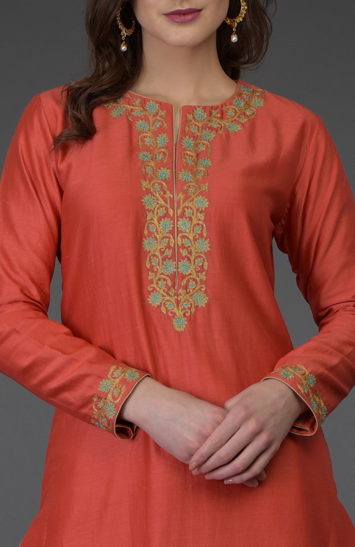 A woman models a living coral resham-tilla embroidered farshi palazzo suit.