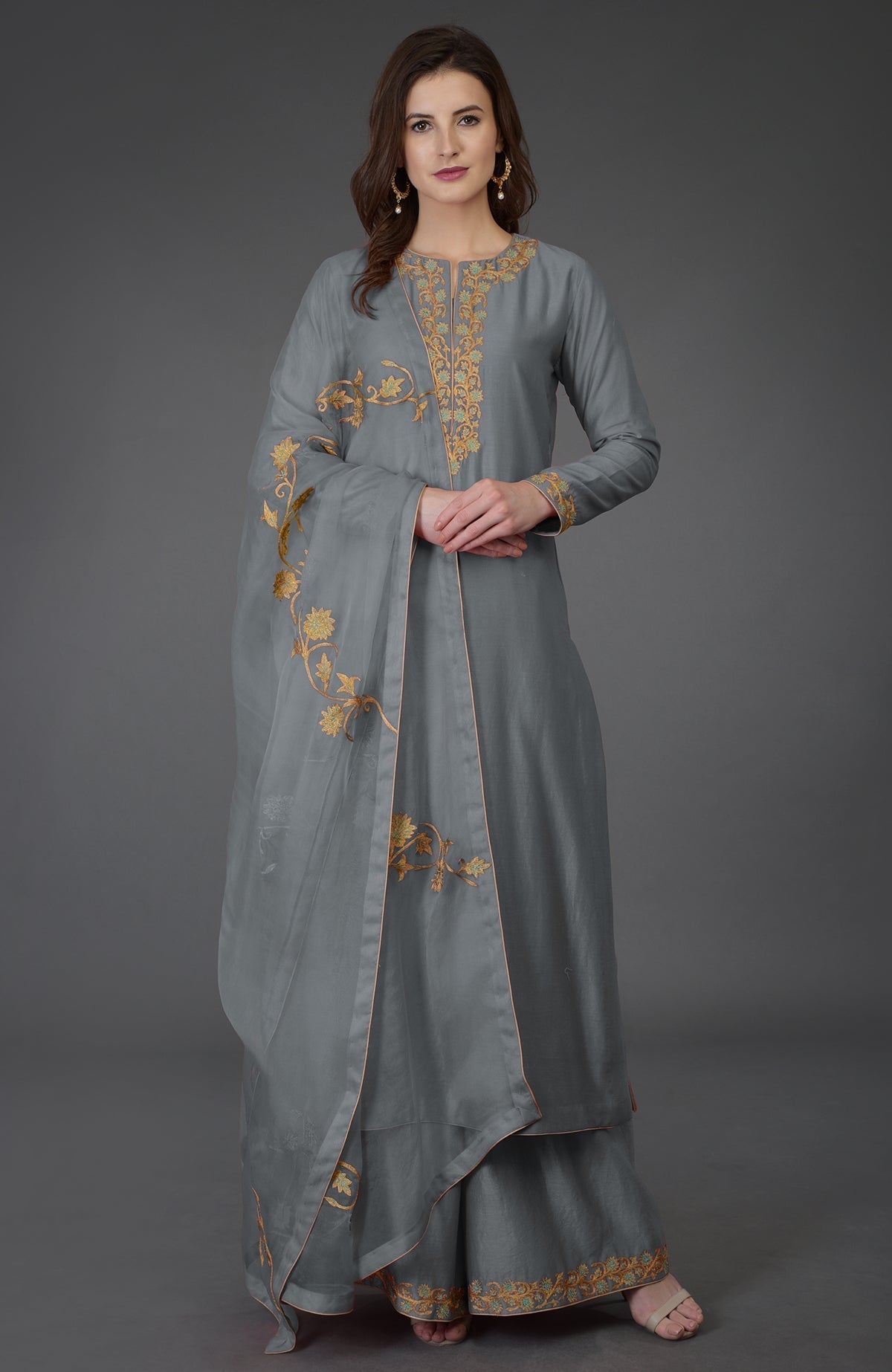 A woman models a gray embroidered farshi palazzo suit with a matching dupatta.