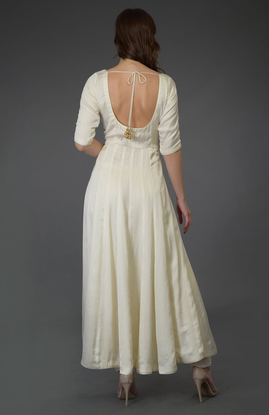 A woman from behind wears an ivory anarkali suit with a scoop back and tie closure.