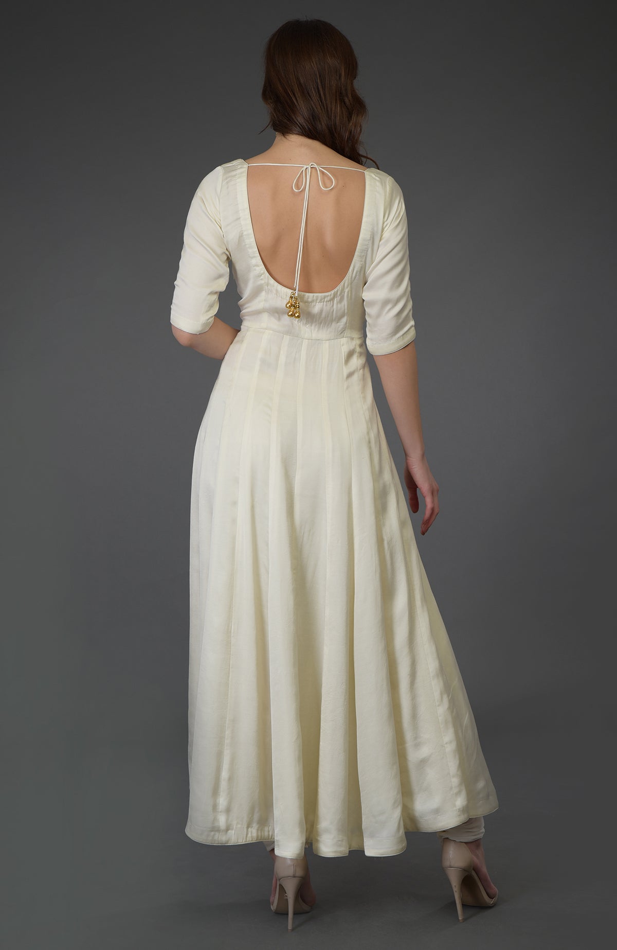 A woman from behind wears an ivory anarkali suit with a scoop back and tie closure.