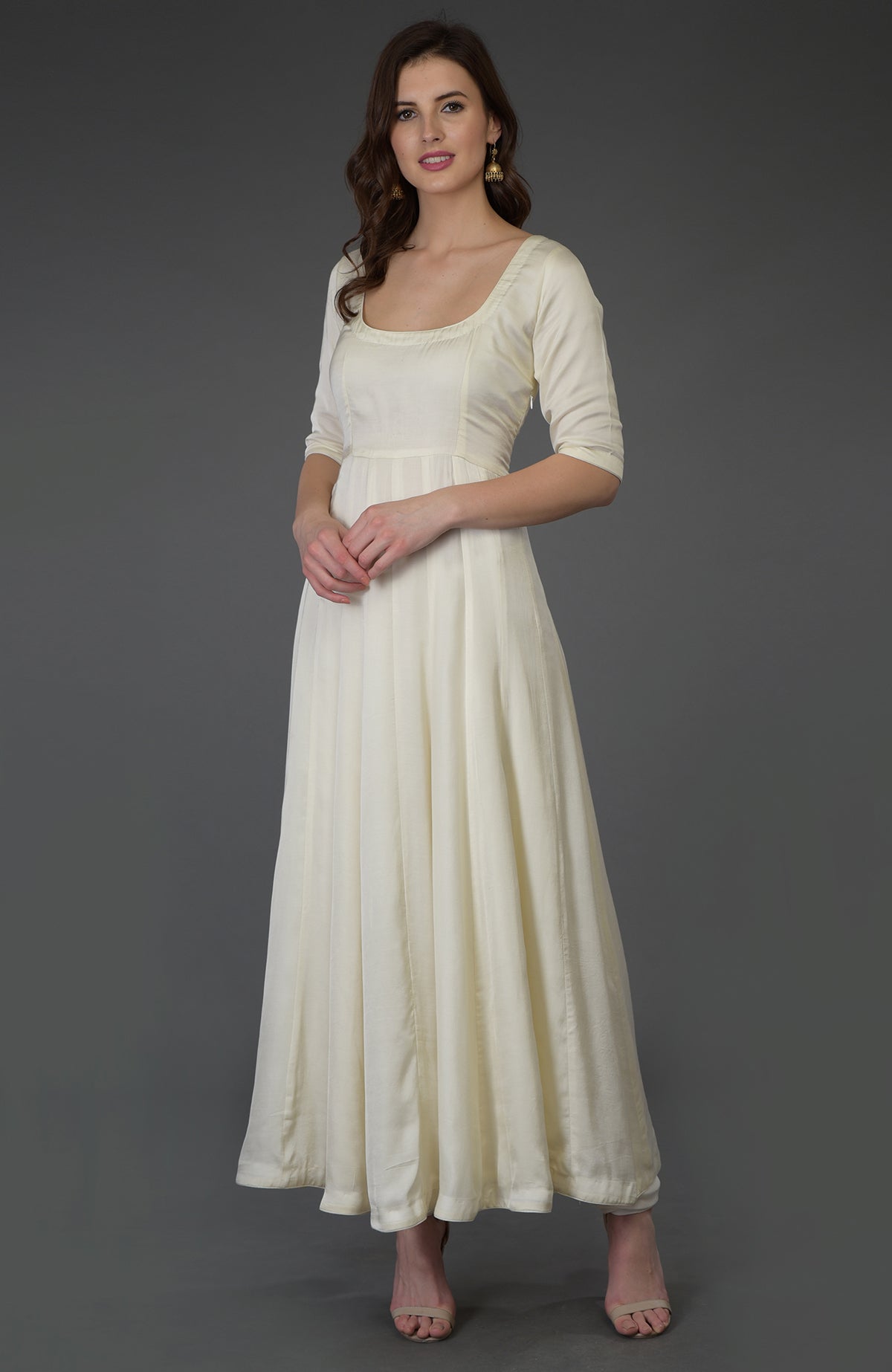 A woman models an ivory scoop neck anarkali suit with three-quarter sleeves.