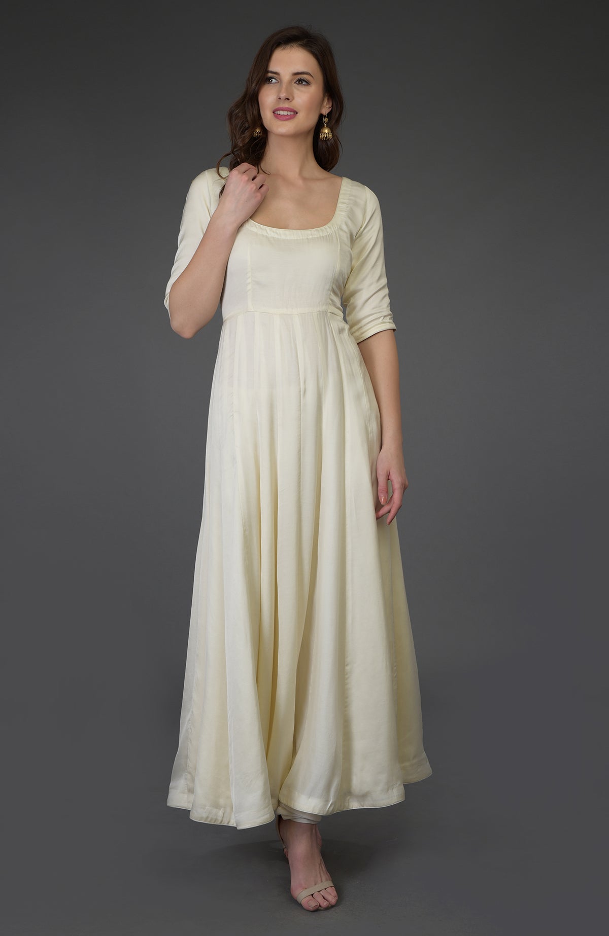 A woman models an ivory scoop neck anarkali suit with three-quarter sleeves.
