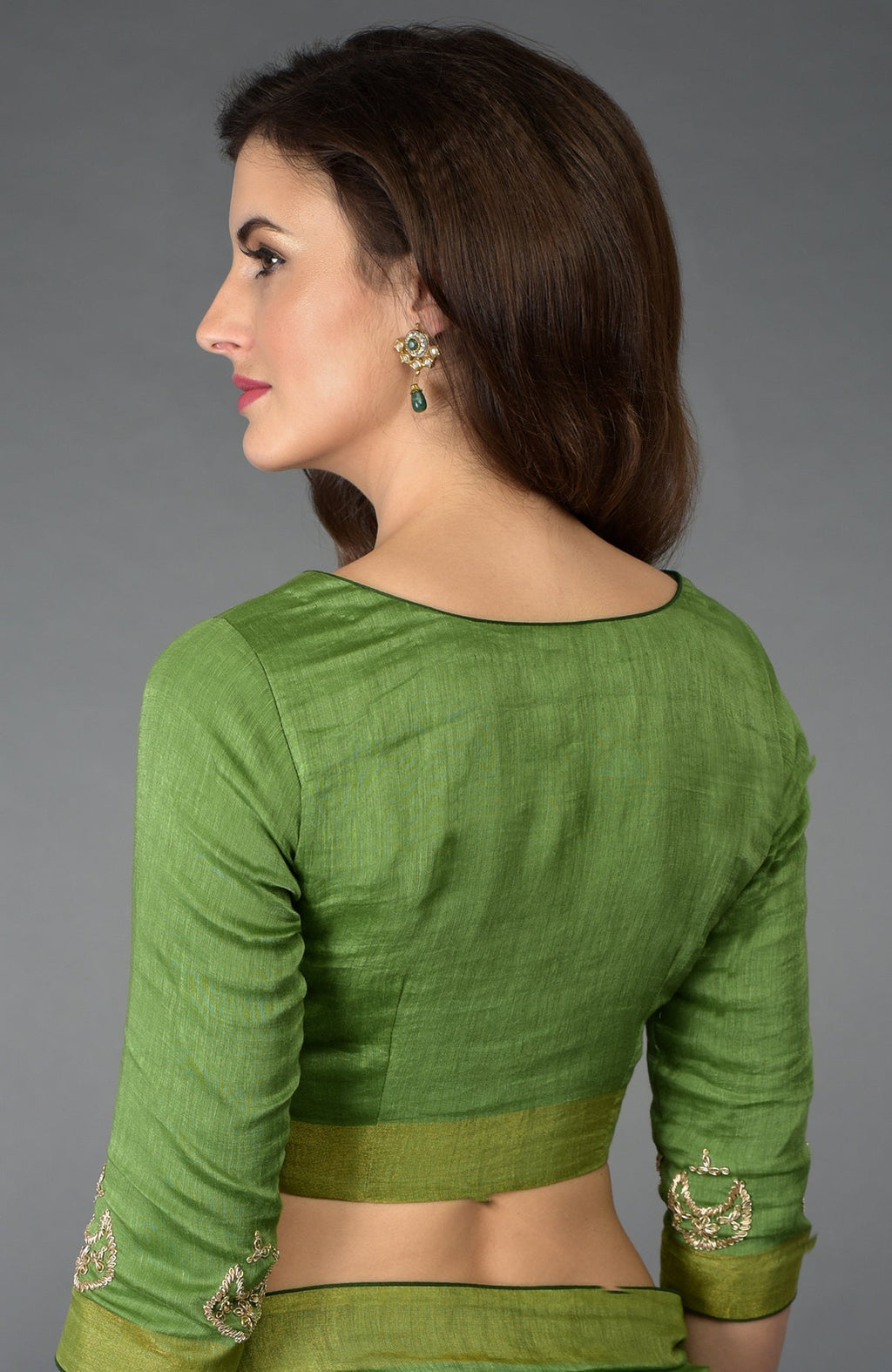 Woman in a green linen saree with embroidered sleeves and matching blouse.