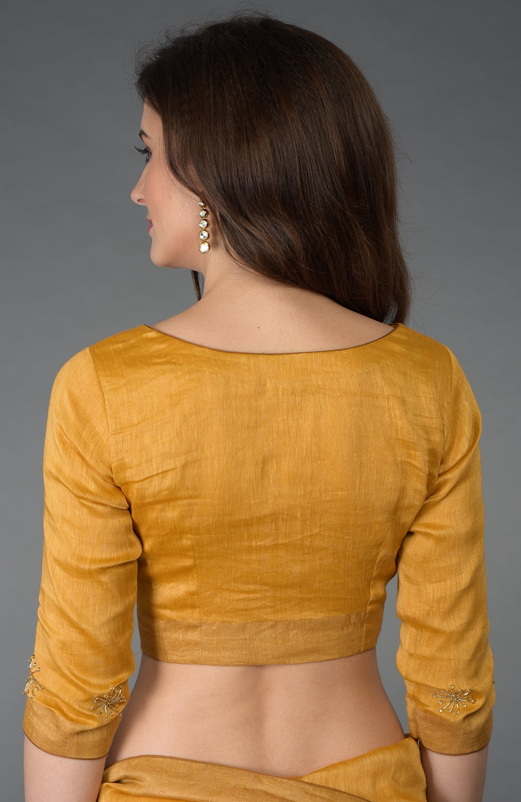 A woman models a citrus linen blouse with gold zardozi embroidery on the sleeves.