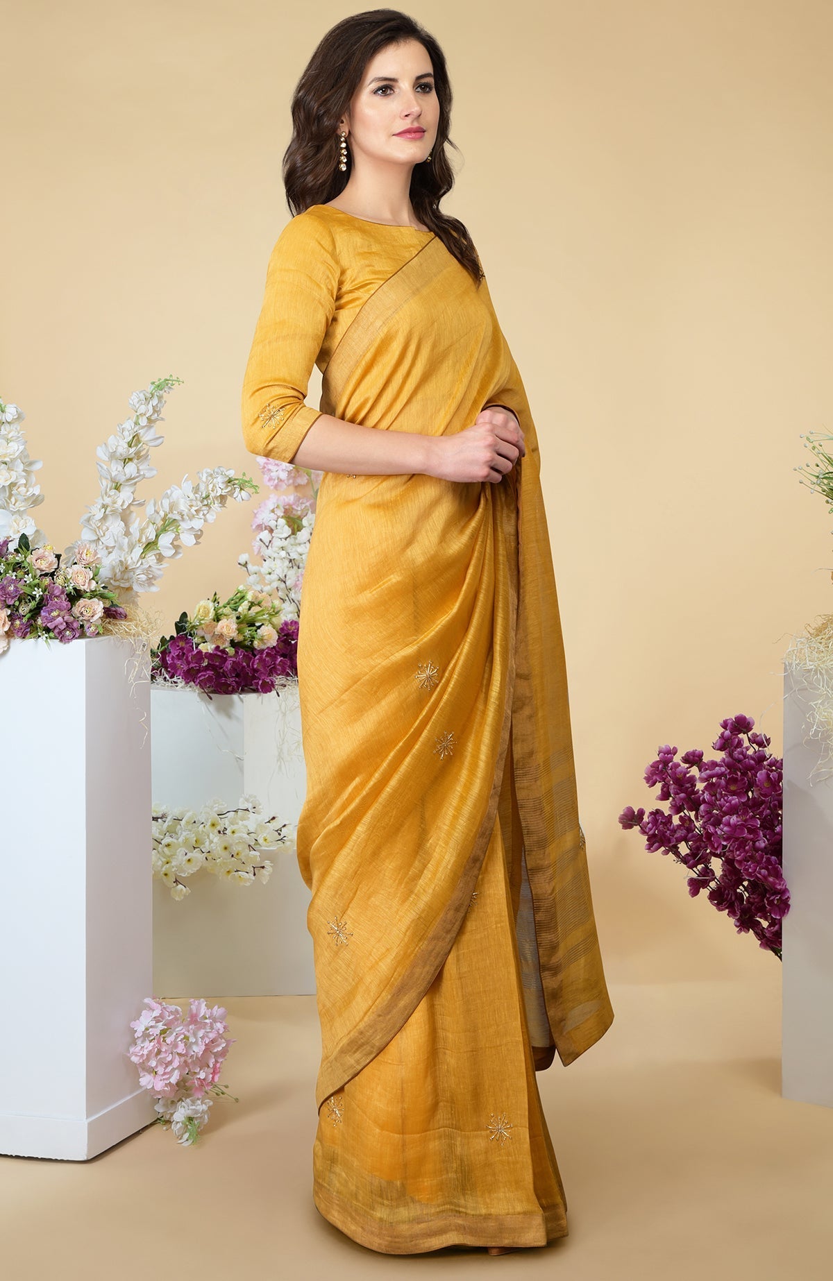 A woman models a citrus linen saree with gold zardozi embroidery and zari borders.