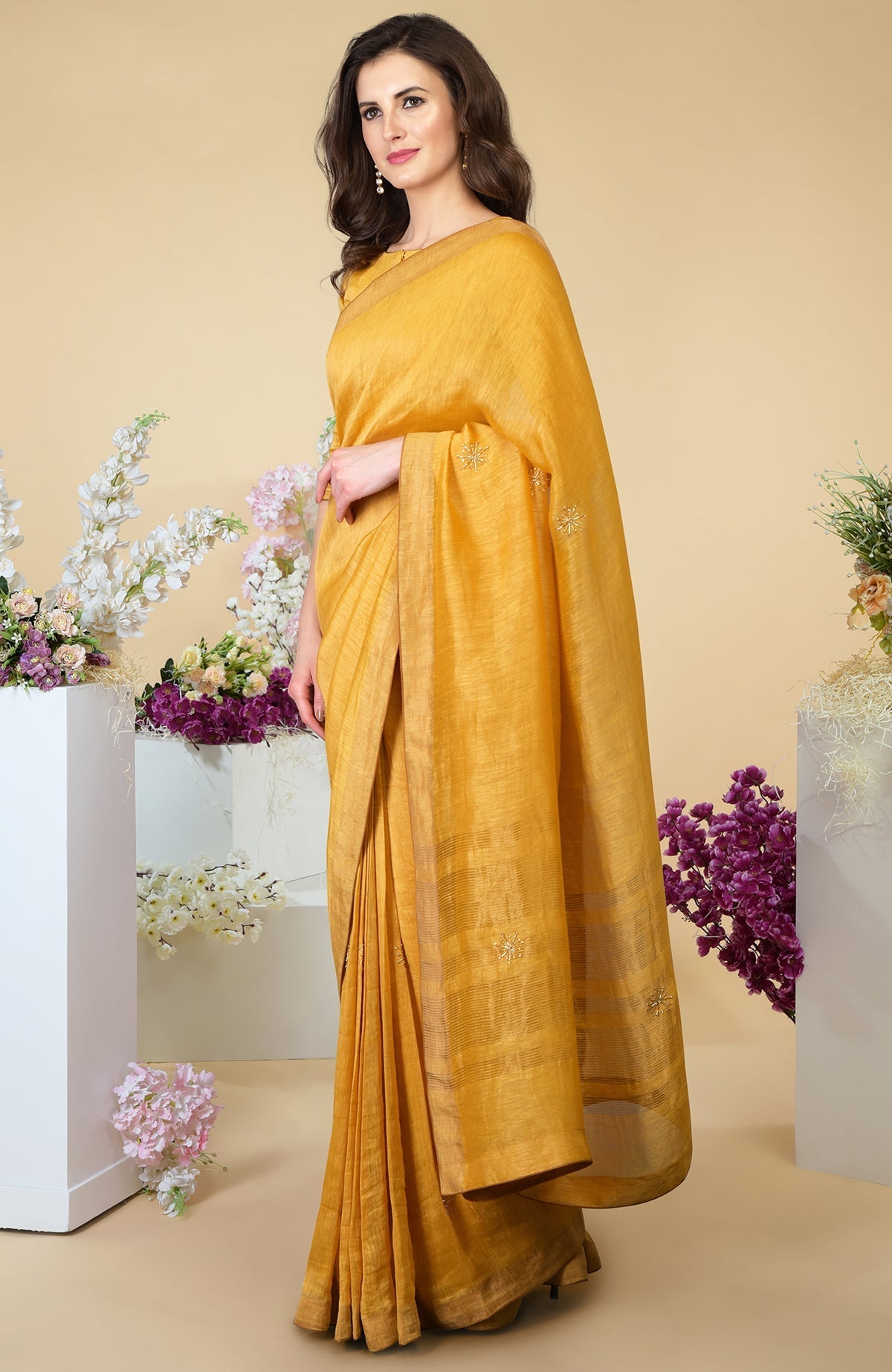 A woman models a citrus linen saree with gold zardozi embroidery and zari borders.