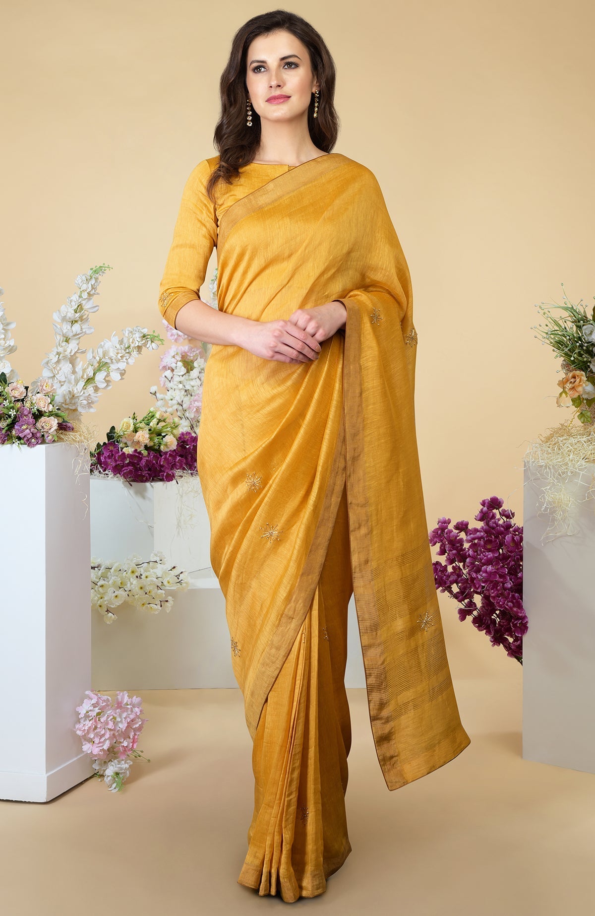 A woman models a citrus linen saree with gold zardozi embroidery and zari borders.
