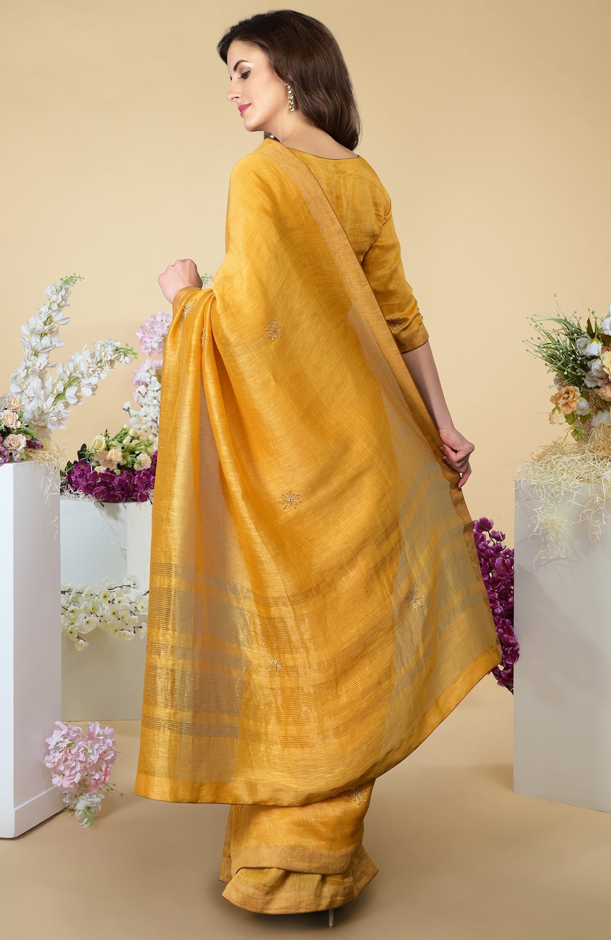 A woman models a citrus linen saree with gold zardozi embroidery and zari borders.