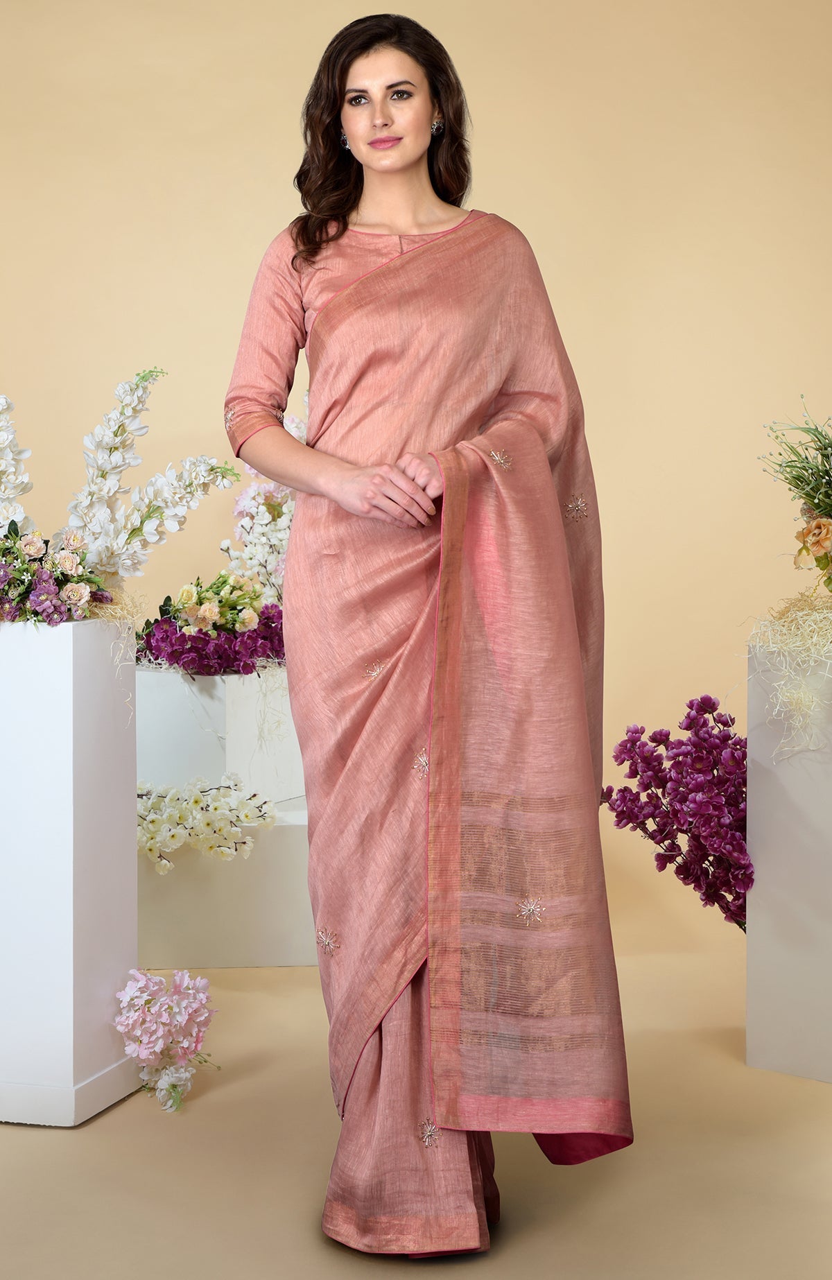 A woman models a pressed rose silk linen saree with zardozi embroidery.
